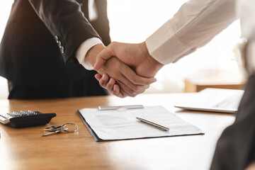 Close up view hands of agent and client shaking hands after signed contract buy new apartment.