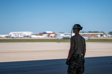 A man in a military uniform stands on the runway, looking out over the tarmac