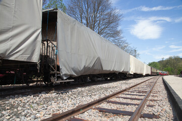 Train en gare avec des wagons empaquetés sous des bâches - obrazy, fototapety, plakaty