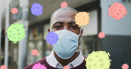 Image of covid 19 cells over african american man wearing face mask