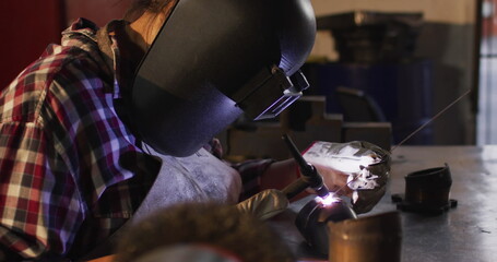A female mechanic is welding while sitting at a car service station