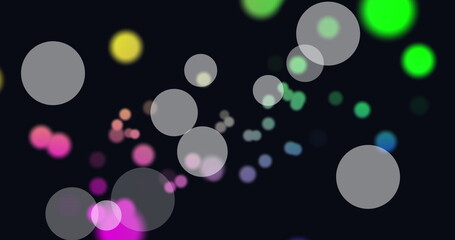 Image of white and colorful spots of light floating against black background