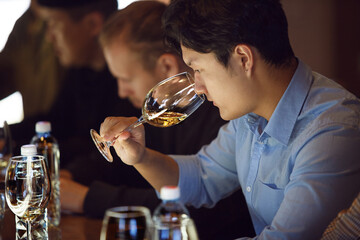 Asian Sommelier Engaged in White Wine Aroma Analysis During Degustation Training Session