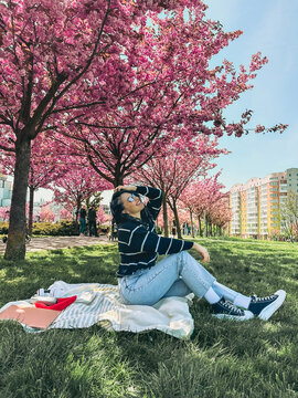 pretty smiling woman posing in front of blooming sakura trees