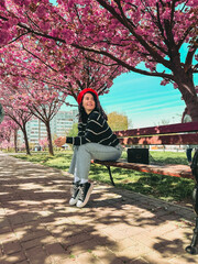 pretty smiling woman posing in front of blooming sakura trees