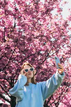 happy woman taking selfie on the phone in front of blooming sakura