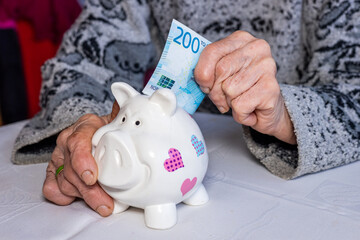 Norway money, Pensioner puts 200 Norwegian kroner into a piggy bank, financial concept, Saving and...