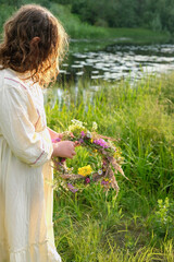 girl with flower wreath outdoor, natural sunny background. rear view. Floral crown, symbol of summer solstice. ceremony for Midsummer, wiccan Litha sabbat. pagan folk holiday Ivan Kupala - obrazy, fototapety, plakaty