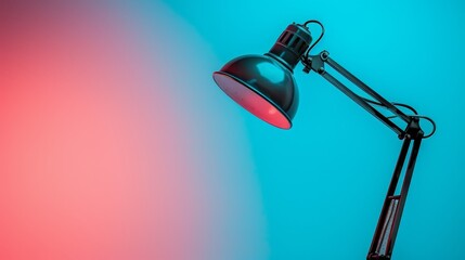   A black desk lamp with a red bulb emits light against a blue-pink background; the lamp's top bears another red light