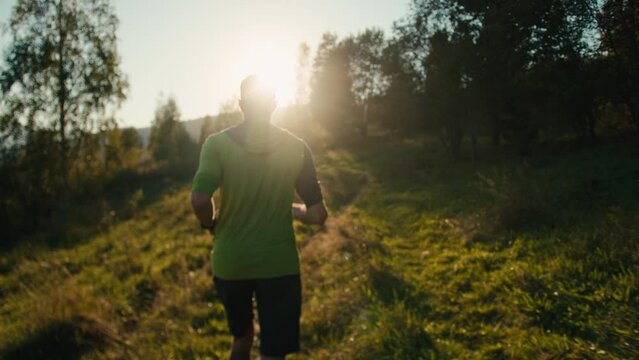 Back view sporty unrecognizable millennial Caucasian male man guy trail runner mountaineer jogging running climbing sprint run route training triathlon sunshine sunrise mountain nature forest outdoors