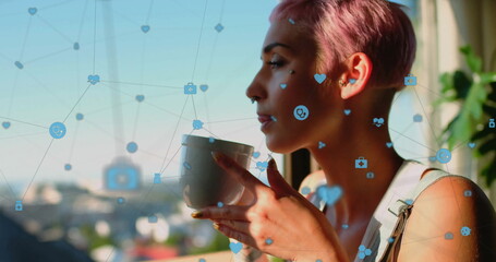 Image of icons connected with lines, biracial woman enjoying coffee while looking through window - Powered by Adobe