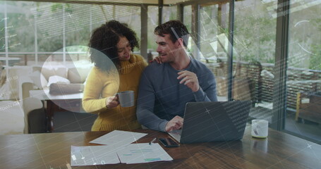 Image of charts and data processing over happy biracial couple using laptop at home