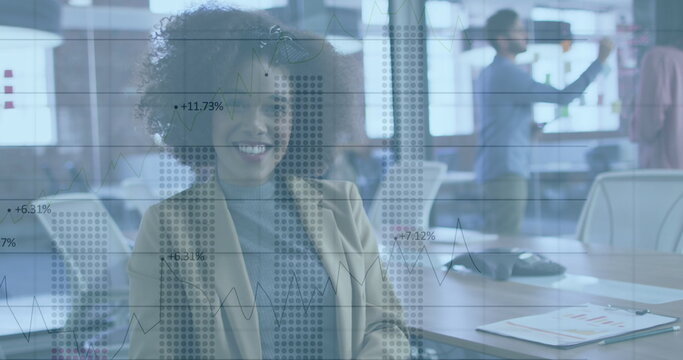 Image of charts and data processing over smiling biracial businesswoman in office