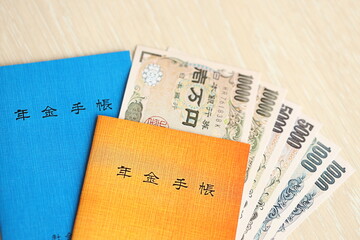 Japanese pension insurance booklets on table with yen money bills. Blue and orange books for japan...