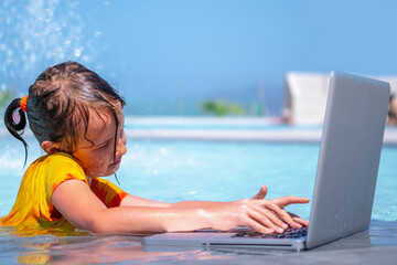Learning and study everywhere and always concept. Portrait of young girl learning with laptop computer in the swimming pool water. Copy space for design or text.