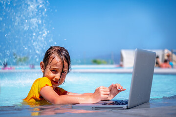 Conceptual image of distance learning. Portrait of young beautiful happy girl learning with laptop computer in the swimming pool. Selective focus. Horizontal image.