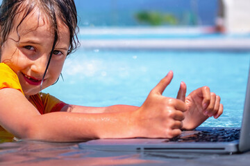 Conceptual image of distance learning. Portrait of young beautiful happy girl learning with laptop computer in the swimming pool. Selective focus on eyes. Horizontal image.