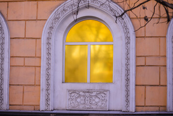 white arched window with an ornament around and gold panes