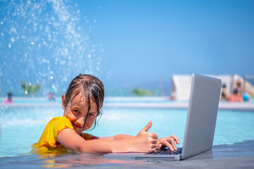Conceptual image of distance learning. Portrait of young beautiful happy girl learning with laptop computer in the swimming pool. Selective focus.