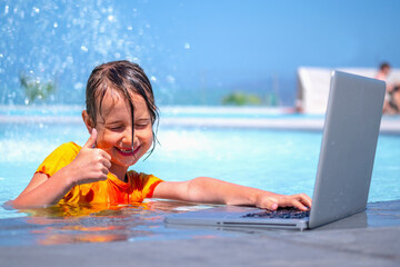 Distance learning. Portrait of young beautiful happy girl learning with laptop computer in the swimming pool.