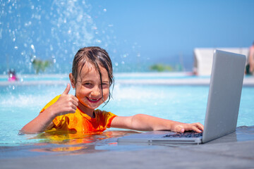 Distance Learning, learning and study everywhere and always. Young happy girl learning with laptop computer in the swimming pool. Horizontal image.