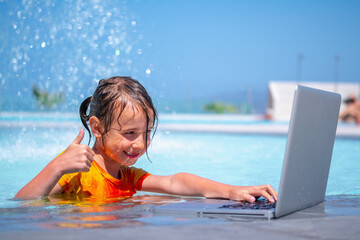 Distance Learningю Learning and study everywhere and always. Young girl learning with laptop computer in the swimming pool water. Horizontal image.
