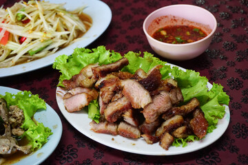 Grilled Pork Neck in Thai style, on white dish and other food on table