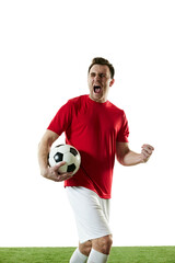 Emotive football player in red t-shirt and white shorts standing with ball on field and shouting isolated on white background. Concept of professional sport, game, competition, tournament, action - obrazy, fototapety, plakaty