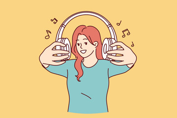Wireless headphones in hands of woman inviting you to listen to popular songs or radio broadcasts together. Cheerful girl with headphones, proud of collected playlist of rare compositions - 785549812