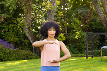 Young biracial woman with curly black hair practicing yoga in garden at home