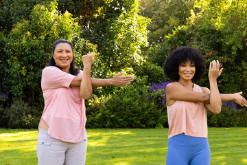 Mature biracial woman and young biracial woman exercising in garden at home
