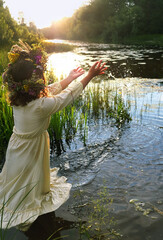girl in flower wreath stand in river. summer nature background. Floral crown, symbol of summer solstice. ceremony for Midsummer, wiccan Litha sabbat. pagan folk holiday Ivan Kupala - obrazy, fototapety, plakaty