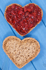 Slice of bread with strawberry jam for breakfast. Shape of heart