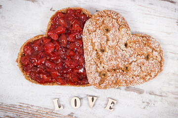 Bread in shape of heart with strawberry jam and inscription love. Rustic background