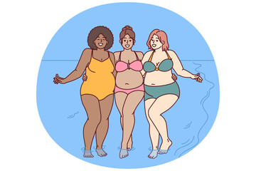 Cheerful plus size women dressed in swimsuit stand hugging on sunny beach near sea water and look at camera smiling. Diverse plus size girls for concept of no prejudice and body positivity - 785552008