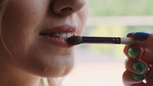 makeup artist paints girl's lips