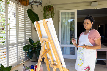 Mature biracial woman painting on canvas at home - Powered by Adobe