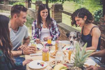 Group of friends eat in a farmhouse in the countryside. Moments of happiness and positive...