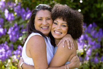 Mother and Daughter, biracial mature woman and young woman hugging, smiling at home in the garden