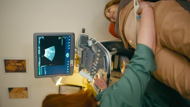 A pregnant woman looks at the screen of the ultrasound diagnostic machine. She asks the doctor about her child. High quality 4k footage