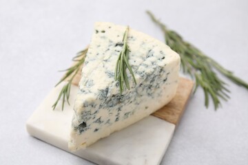 Tasty blue cheese with rosemary on light table, closeup