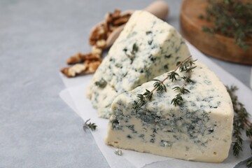 Tasty blue cheese with thyme on grey table, closeup. Space for text
