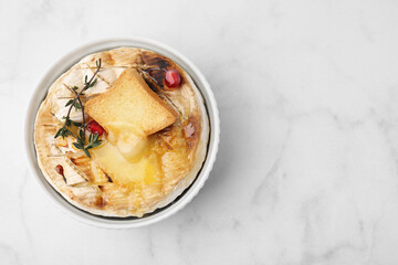 Tasty baked camembert with crouton and thyme on white marble table, top view. Space for text