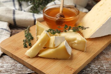 Tasty Camembert cheese with thyme and honey on wooden table