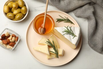 Fototapeta premium Tasty Camembert cheese with rosemary and honey on white table, flat lay