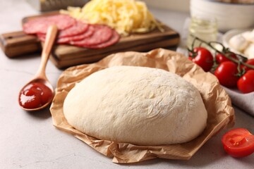 Pizza dough and products on gray textured table, closeup