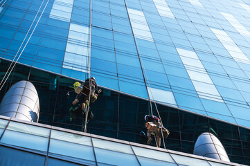 Group of high rise workers hanging on access rope cleaning highrise glass building in Seoul, South...