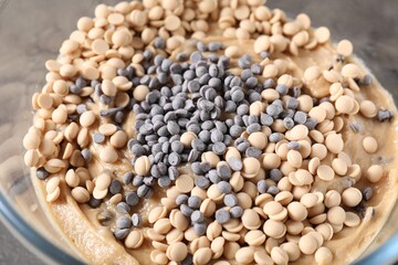 Raw dough with chocolate chips in bowl on grey table, closeup