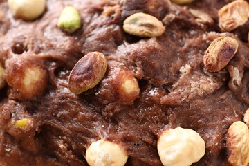 Raw chocolate dough with nuts as background, closeup