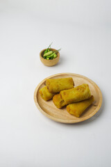 Risoles, a snack from Indonesia served with a little green chili in a wooden plate. Risol and green chilies isolated on a white background